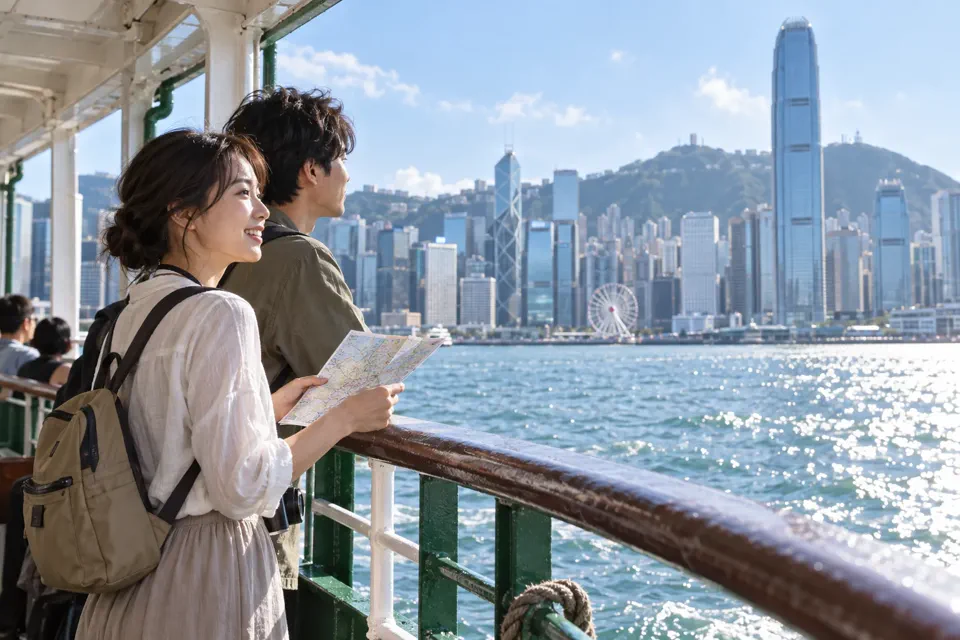 スターフェリーの船上から香港島の高層ビル群を眺める旅行者
