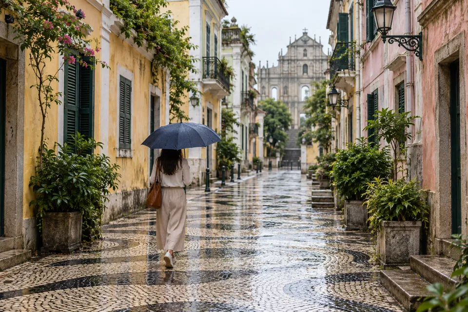 雨上がりのマカオ歴史地区を傘で歩く旅行者